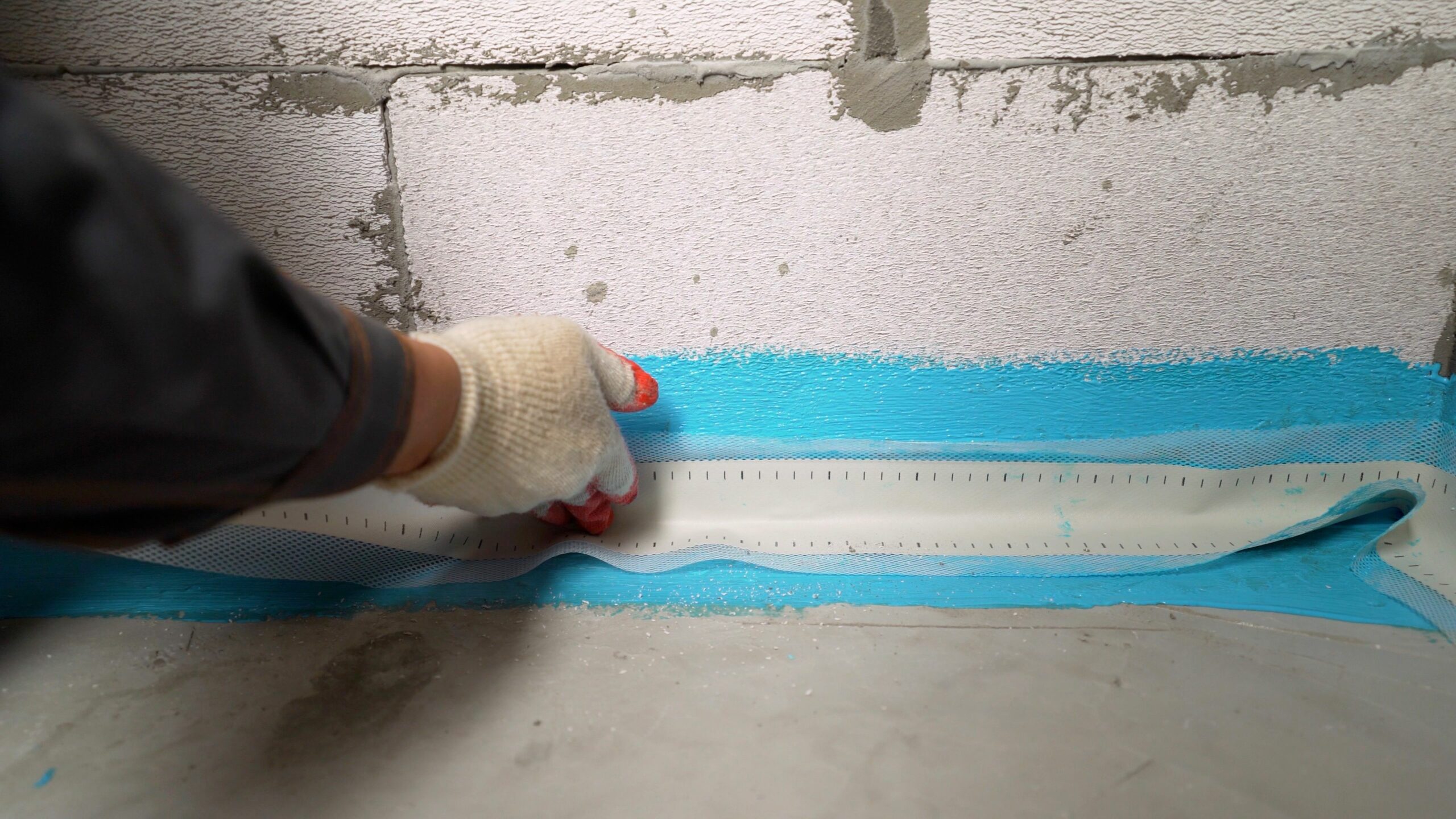Waterproofing the bathroom floor. The proper placement of sealing tape, waterproofing tape in the first layer of waterproofing. Bonding waterproofing tape to the floor.